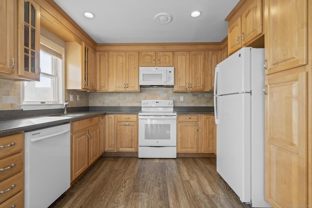 kitchen with dark wood-style flooring, dark countertops, glass insert cabinets, a sink, and white appliances