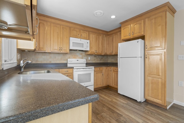 kitchen with white appliances, dark countertops, a sink, and tasteful backsplash