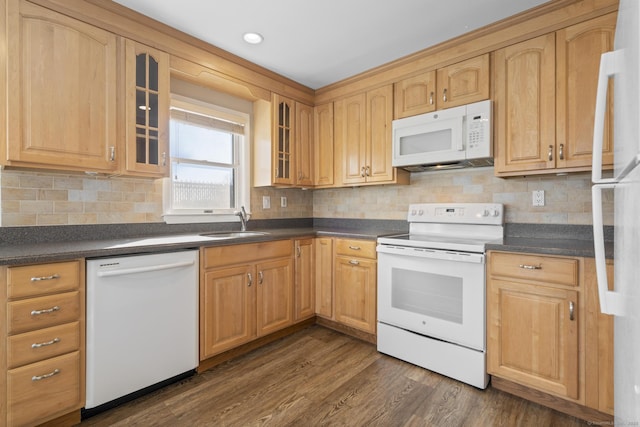 kitchen featuring dark countertops, white appliances, dark wood finished floors, and a sink