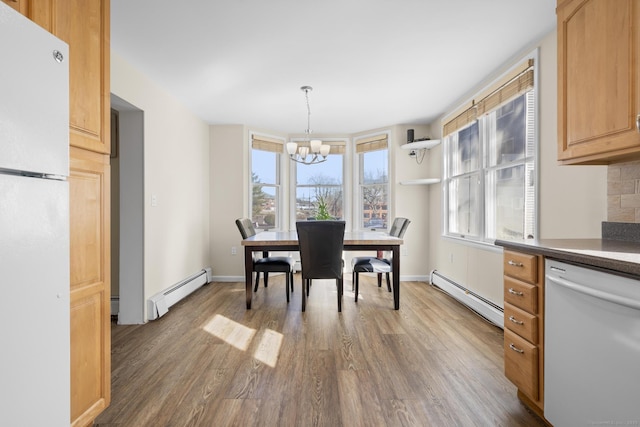 dining room featuring a notable chandelier, baseboards, baseboard heating, and wood finished floors