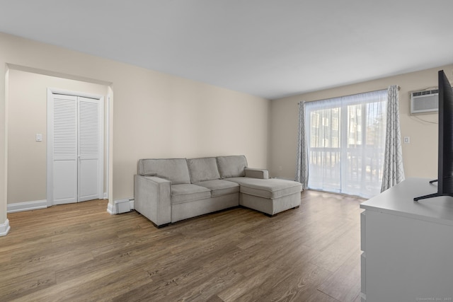 living room with baseboards, a wall mounted AC, baseboard heating, and wood finished floors