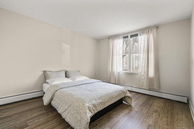 bedroom with a baseboard heating unit and wood finished floors