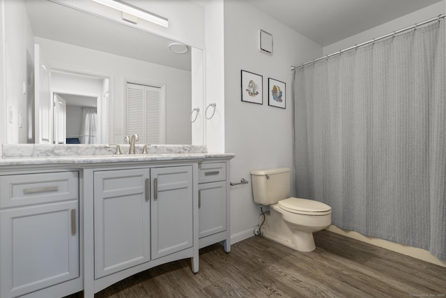 bathroom with baseboards, a shower with shower curtain, toilet, wood finished floors, and vanity