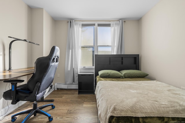 bedroom featuring baseboard heating and wood finished floors