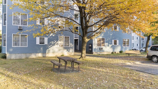 exterior space featuring cooling unit, a lawn, and an AC wall unit