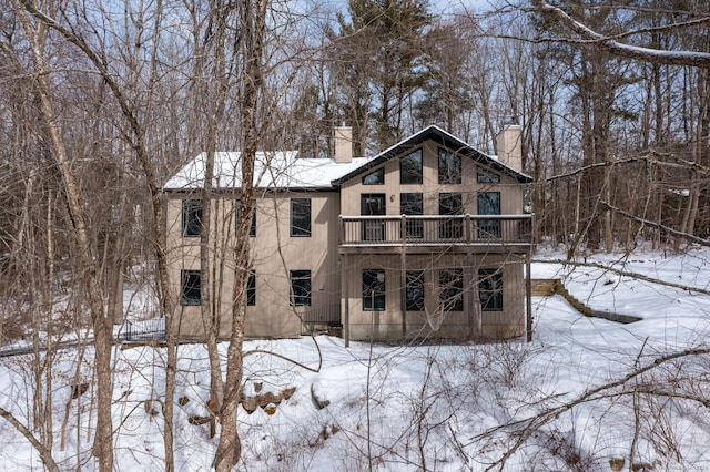 snow covered back of property featuring a chimney