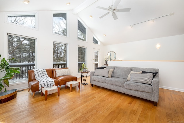 living area with ceiling fan, high vaulted ceiling, light wood-style flooring, baseboards, and beam ceiling