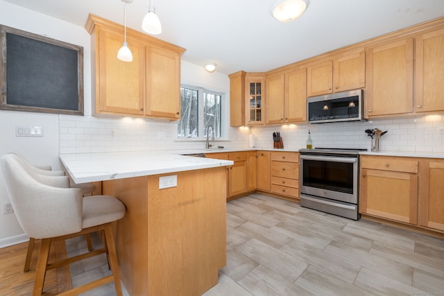 kitchen with stainless steel appliances, decorative backsplash, a peninsula, and a kitchen bar