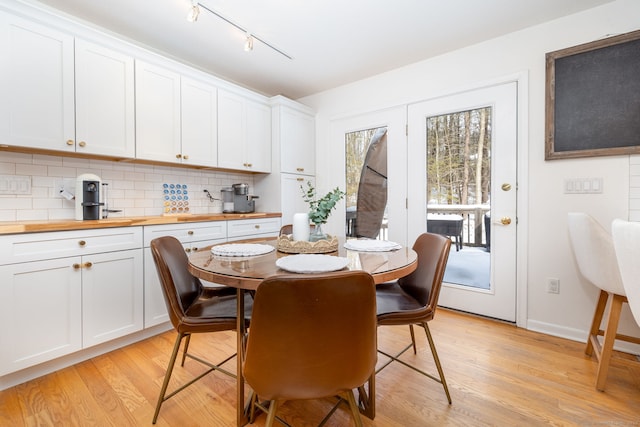 dining area with light wood-style floors, baseboards, and rail lighting