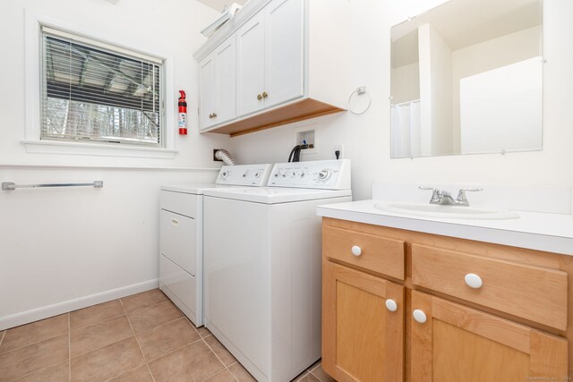 washroom with light tile patterned flooring, a sink, baseboards, cabinet space, and washer and clothes dryer