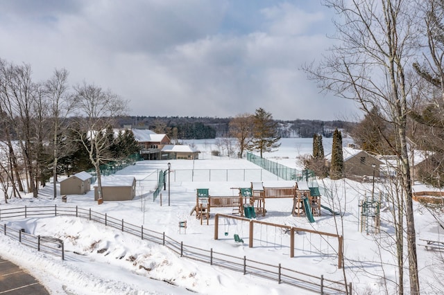 yard layered in snow featuring fence and a playground