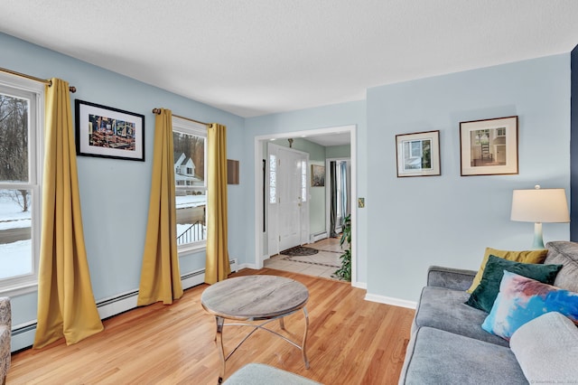 living room with a baseboard radiator, light hardwood / wood-style floors, and a textured ceiling