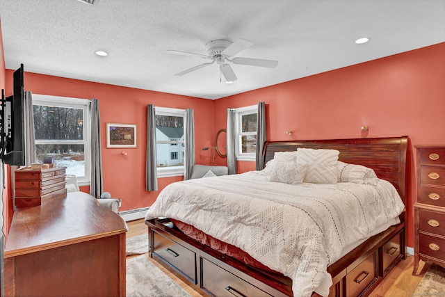 bedroom with a baseboard radiator, ceiling fan, a textured ceiling, and light hardwood / wood-style floors