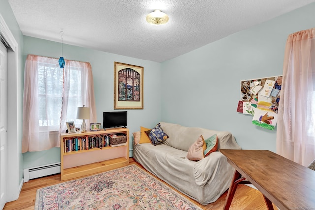 living room with a baseboard heating unit, a textured ceiling, and light wood-type flooring