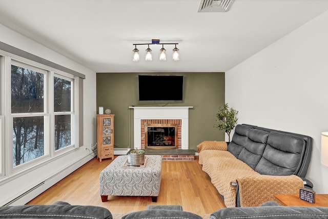 living room with a baseboard radiator, a fireplace, and light hardwood / wood-style flooring