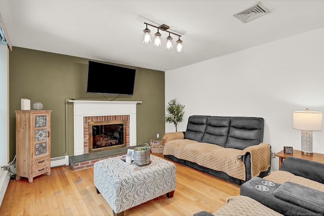 living room with hardwood / wood-style flooring, baseboard heating, and a brick fireplace