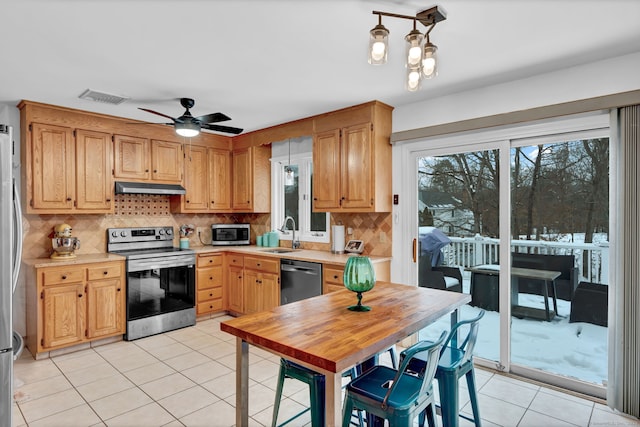 kitchen with sink, tasteful backsplash, light tile patterned floors, appliances with stainless steel finishes, and ceiling fan