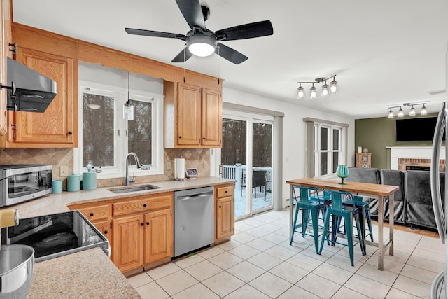 kitchen featuring sink, tasteful backsplash, stainless steel appliances, a fireplace, and wall chimney range hood