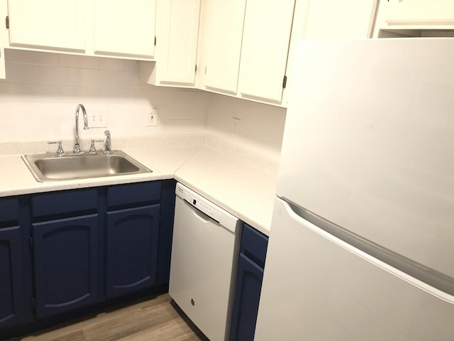 kitchen featuring sink, white appliances, light hardwood / wood-style flooring, tasteful backsplash, and white cabinets