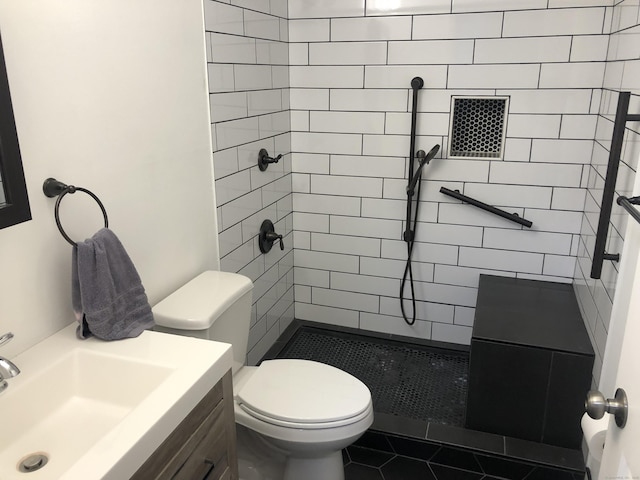 bathroom featuring a tile shower, vanity, tile patterned flooring, and toilet