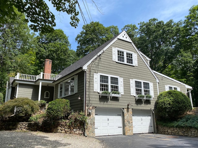 view of front of home featuring driveway, a chimney, and an attached garage