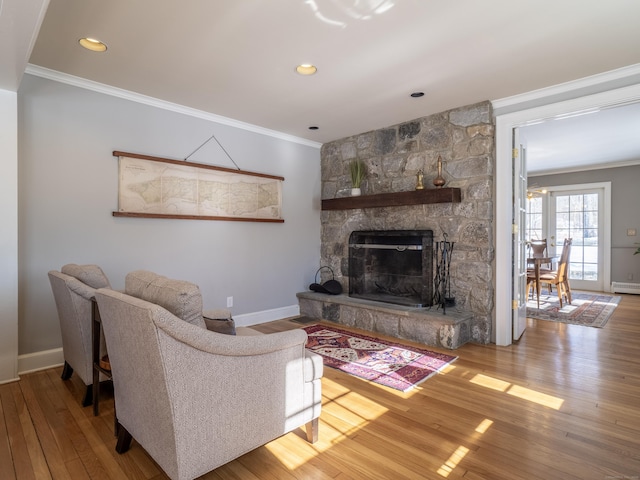 living room featuring a fireplace, baseboards, crown molding, and wood finished floors