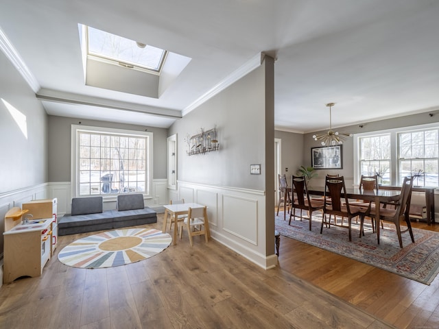 living area with a skylight, a wainscoted wall, a healthy amount of sunlight, and wood finished floors