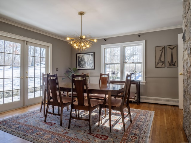 dining room featuring a baseboard heating unit, a notable chandelier, crown molding, and wood finished floors