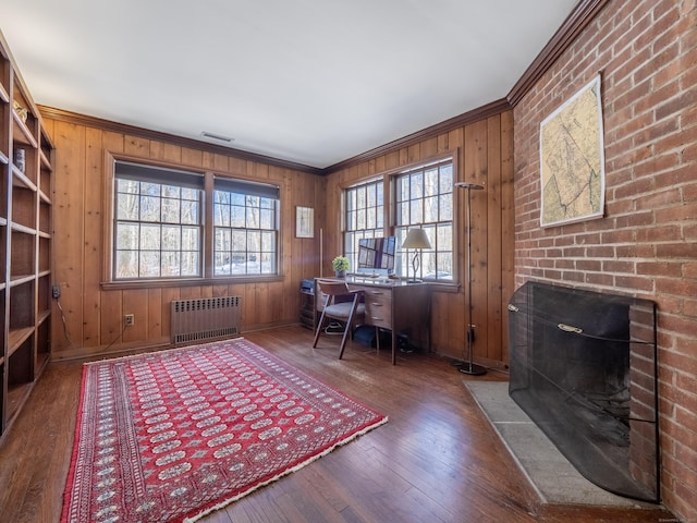 unfurnished office with dark wood-style floors, a fireplace, crown molding, and radiator heating unit