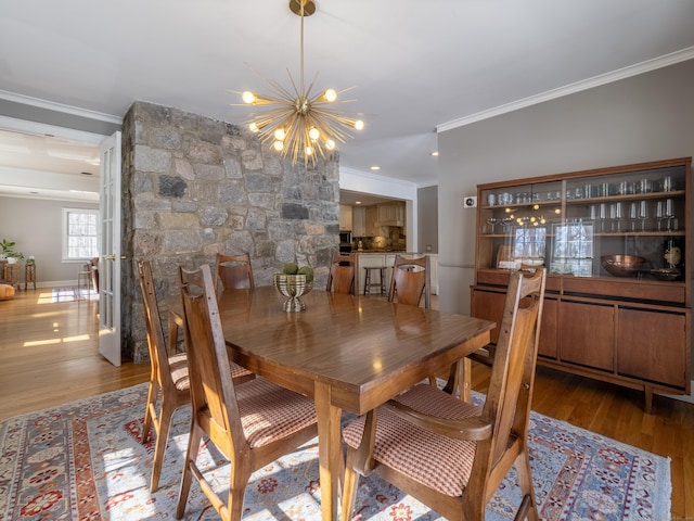 dining room with an inviting chandelier, crown molding, and wood finished floors