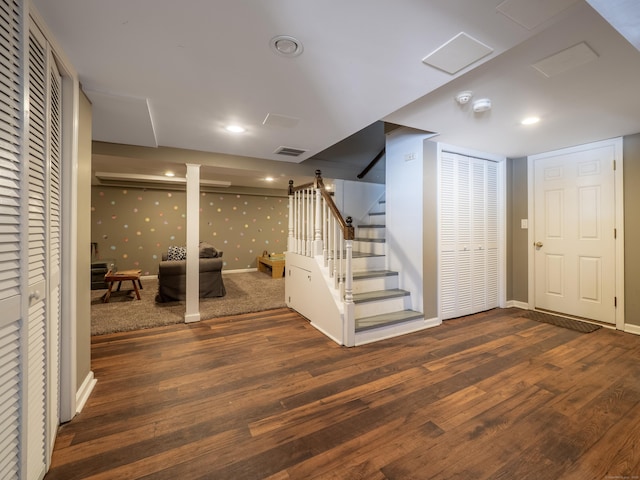 finished basement featuring dark wood-type flooring, stairs, baseboards, and wallpapered walls