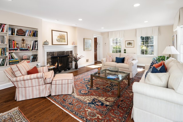 living area featuring recessed lighting, wood finished floors, baseboards, and a high end fireplace