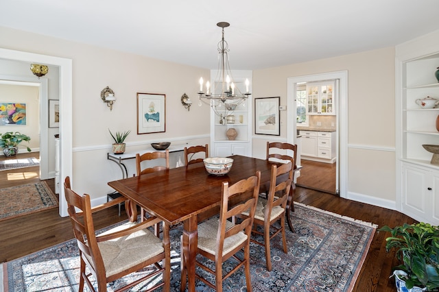 dining room featuring baseboards, dark wood-type flooring, and an inviting chandelier