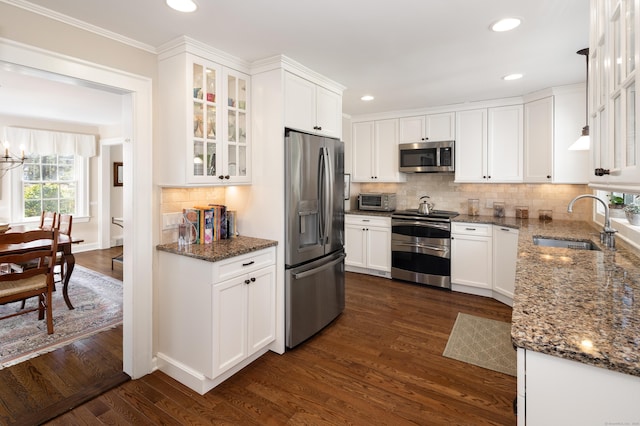 kitchen with dark stone countertops, appliances with stainless steel finishes, dark wood finished floors, and white cabinets