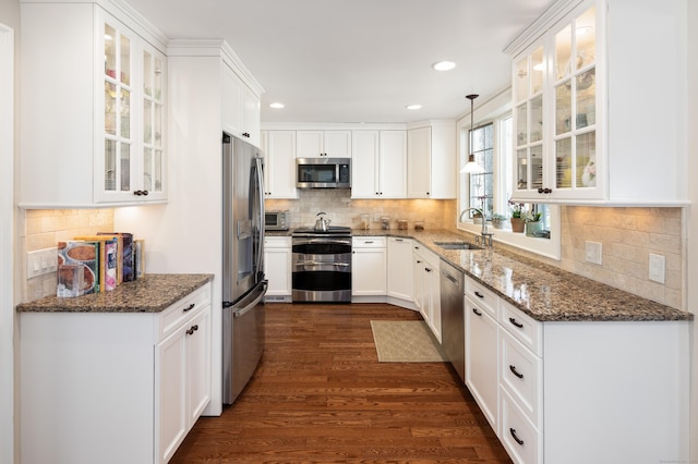 kitchen featuring backsplash, dark wood finished floors, appliances with stainless steel finishes, white cabinets, and a sink