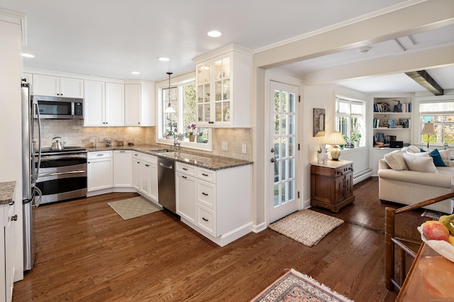 kitchen with a baseboard heating unit, dark wood finished floors, open floor plan, stainless steel appliances, and a sink