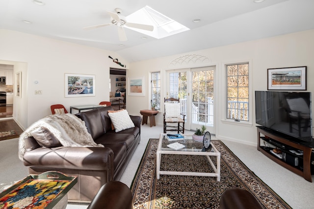 carpeted living area with lofted ceiling with skylight, a ceiling fan, and baseboards