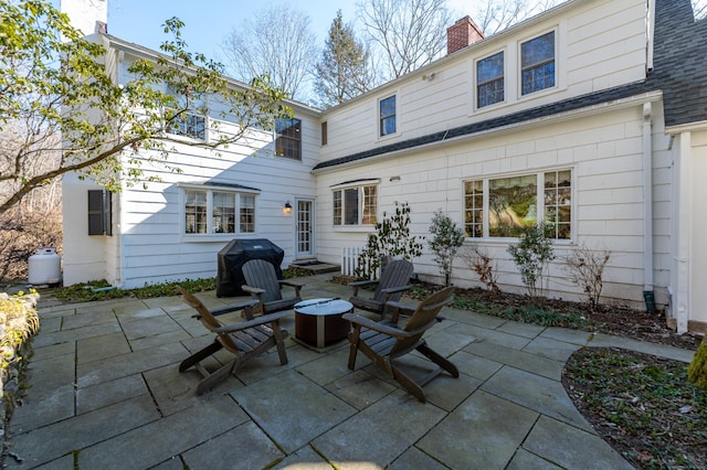 back of property featuring roof with shingles, a chimney, and a patio area