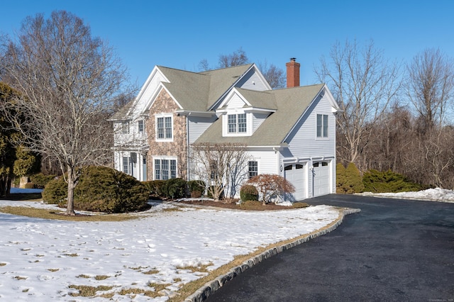 view of front of property featuring driveway, a chimney, and an attached garage