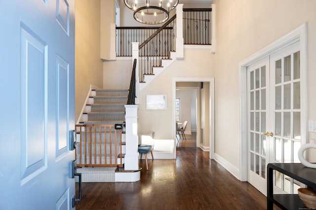 foyer featuring baseboards, dark wood-style flooring, a high ceiling, stairs, and a notable chandelier