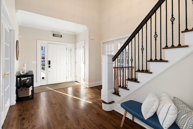 foyer with dark wood-style floors, baseboards, stairs, and crown molding