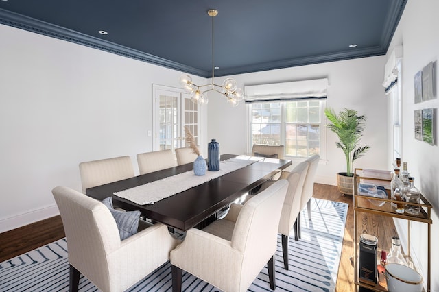 dining room featuring baseboards, a wall unit AC, ornamental molding, wood finished floors, and a chandelier