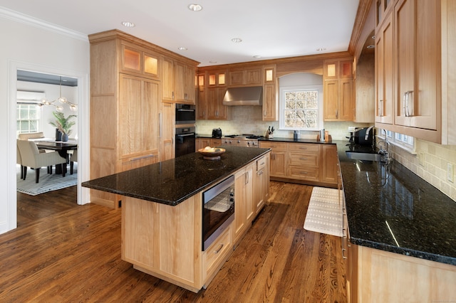 kitchen with under cabinet range hood, a kitchen island, appliances with stainless steel finishes, and dark stone counters