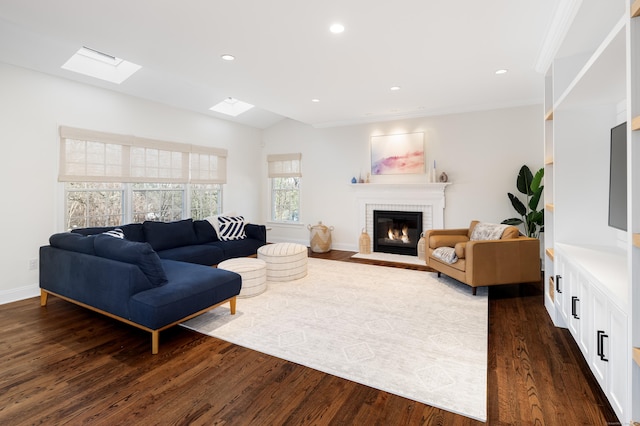 living room with baseboards, lofted ceiling with skylight, dark wood-type flooring, a brick fireplace, and recessed lighting