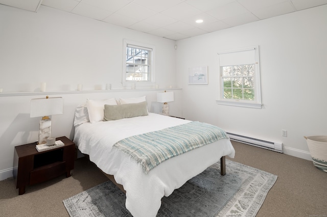 bedroom featuring a baseboard heating unit, carpet, a drop ceiling, and baseboards