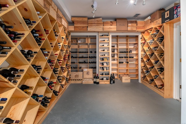 wine area featuring finished concrete floors and track lighting