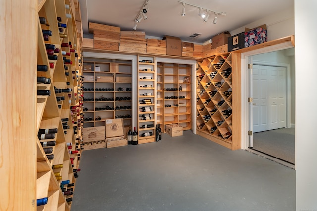 wine room featuring visible vents, finished concrete flooring, and track lighting