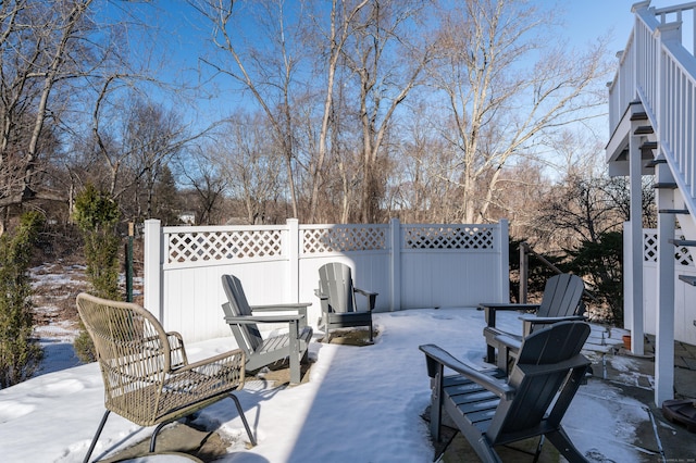 snow covered patio featuring fence