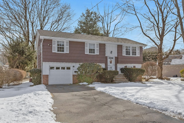 split foyer home featuring aphalt driveway, a garage, and brick siding