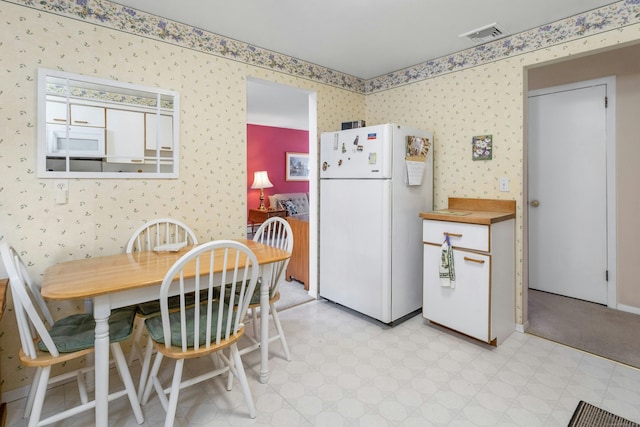 kitchen with visible vents, white appliances, light floors, and wallpapered walls